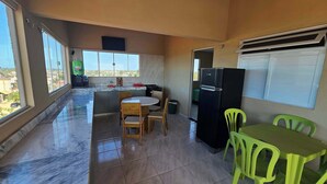 A compact kitchen with a dining area, a refrigerator, and a view of the city. - Penthouse by the Beach Near Rancho do Peixe & Jeri (Preá - CE)