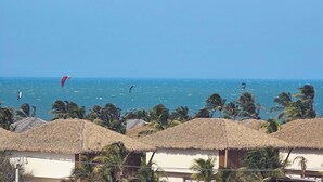 A beach with thatched-roof huts and a view of the sea. - Penthouse by the Beach Near Rancho do Peixe & Jeri (Preá - CE)