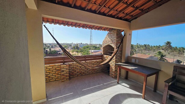 A balcony with a hammock, a brick oven, and a view of palm trees and buildings. - Penthouse by the Beach Near Rancho do Peixe & Jeri (Preá - CE)