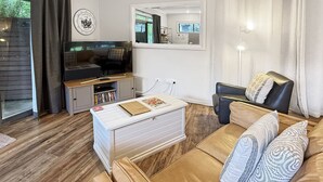 Moderni olohuone, jossa on sohva, sohvapöytä, televisio ja kirjahylly.