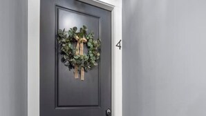 A dark grey door with a wreath, a white trim, and a number '4' on the wall. - Downtown Urban Loft #4 (Perryville)