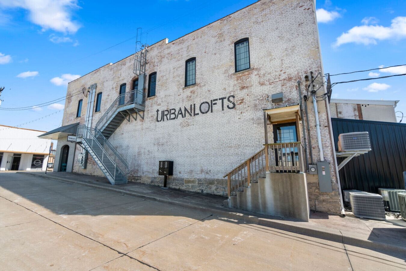 A building with a sign reading "URBANLOFTS" and a staircase leading to an entrance.