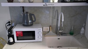 A compact kitchen with a white microwave, a coffee maker, a sink, and a dishwasher.