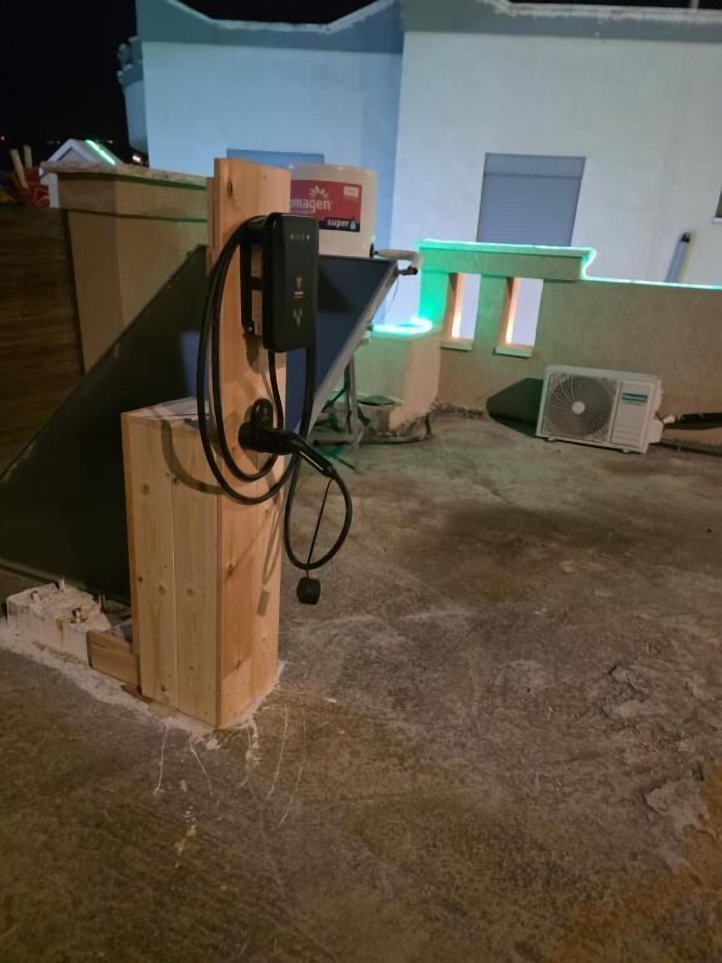 A wooden structure with a power outlet and a fan on the ground.