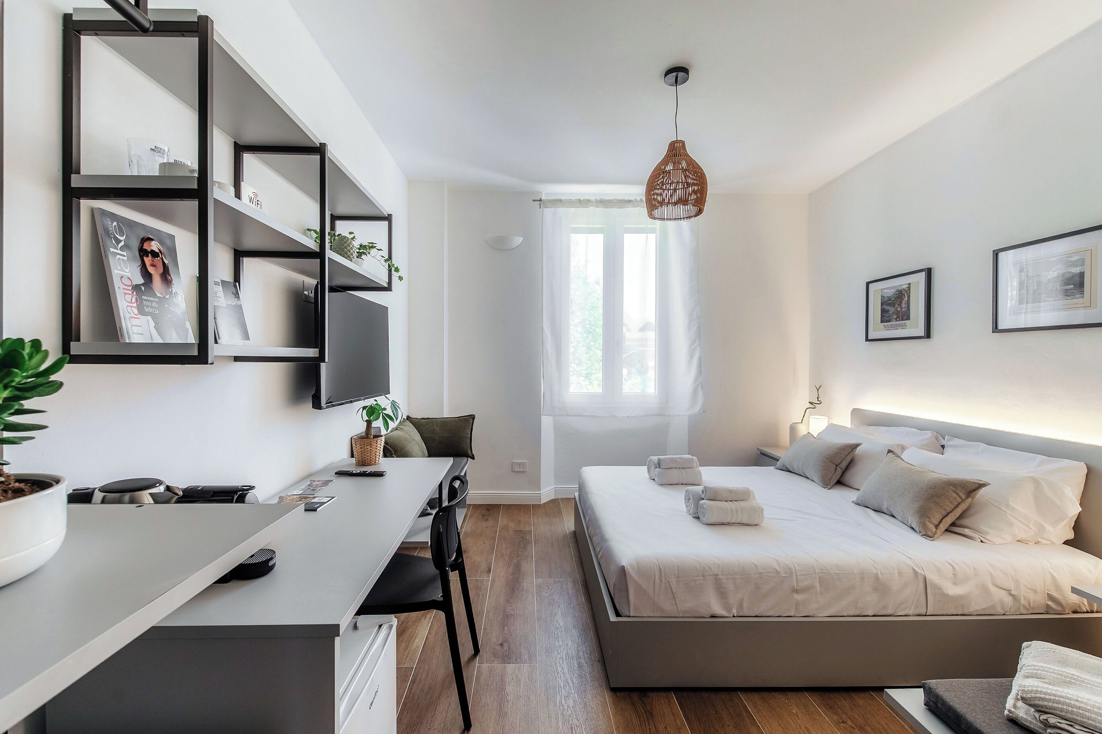 Ein modernes Schlafzimmer mit einem Bett, Nachttischen, einem Schreibtisch und einem großen Fenster.