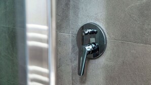 A bathroom with a modern showerhead mounted on a tiled wall. - Batèl House 5 (Como)