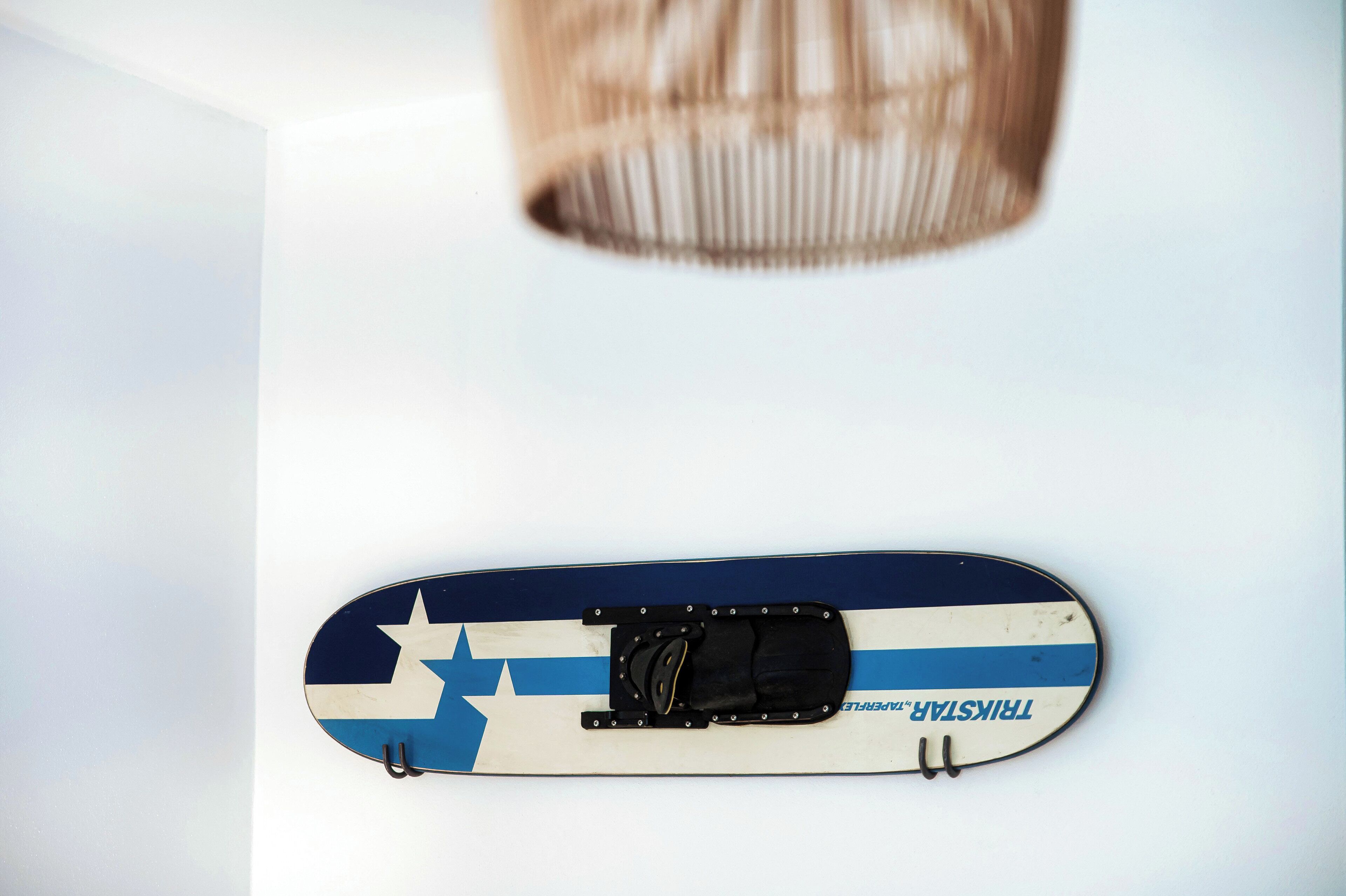 Une planche de skate décorée d’un motif étoilé et rayé, fixée au mur.
