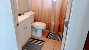 A small bathroom with a toilet, a sink, and a shower curtain.