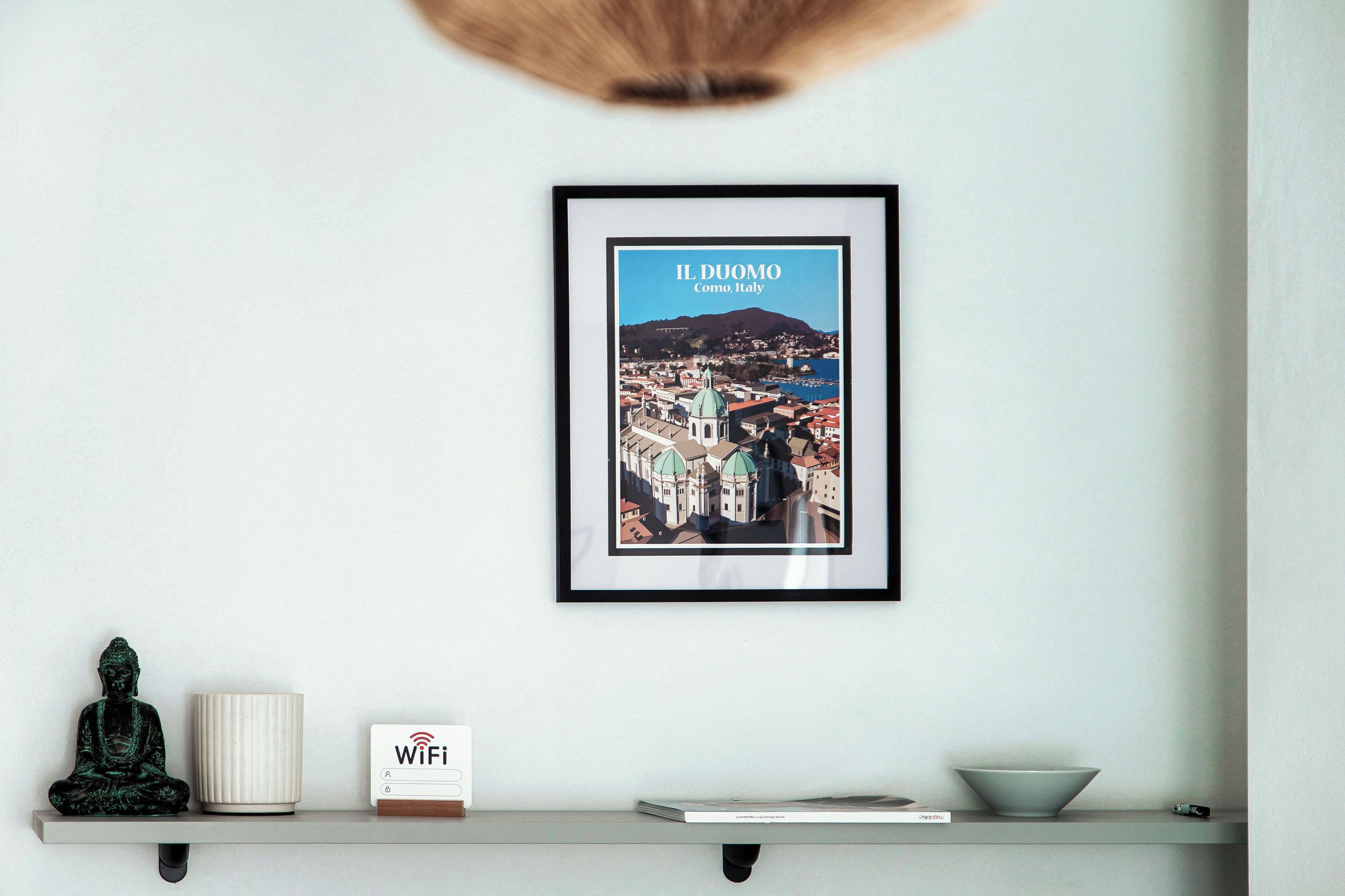 Une affiche encadrée représentant le paysage urbain de Côme, en Italie, est accrochée au mur.