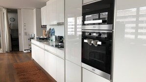 A modern kitchen with white cabinetry, a built-in oven, and a coffee machine. - Modern and bright home by Prime Tower with workspaces & balcony (Zürich)