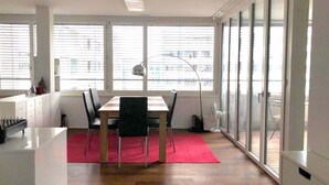 A modern kitchen with a dining area, large windows, and a view of the city. - Modern and bright home by Prime Tower with workspaces & balcony (Zürich)