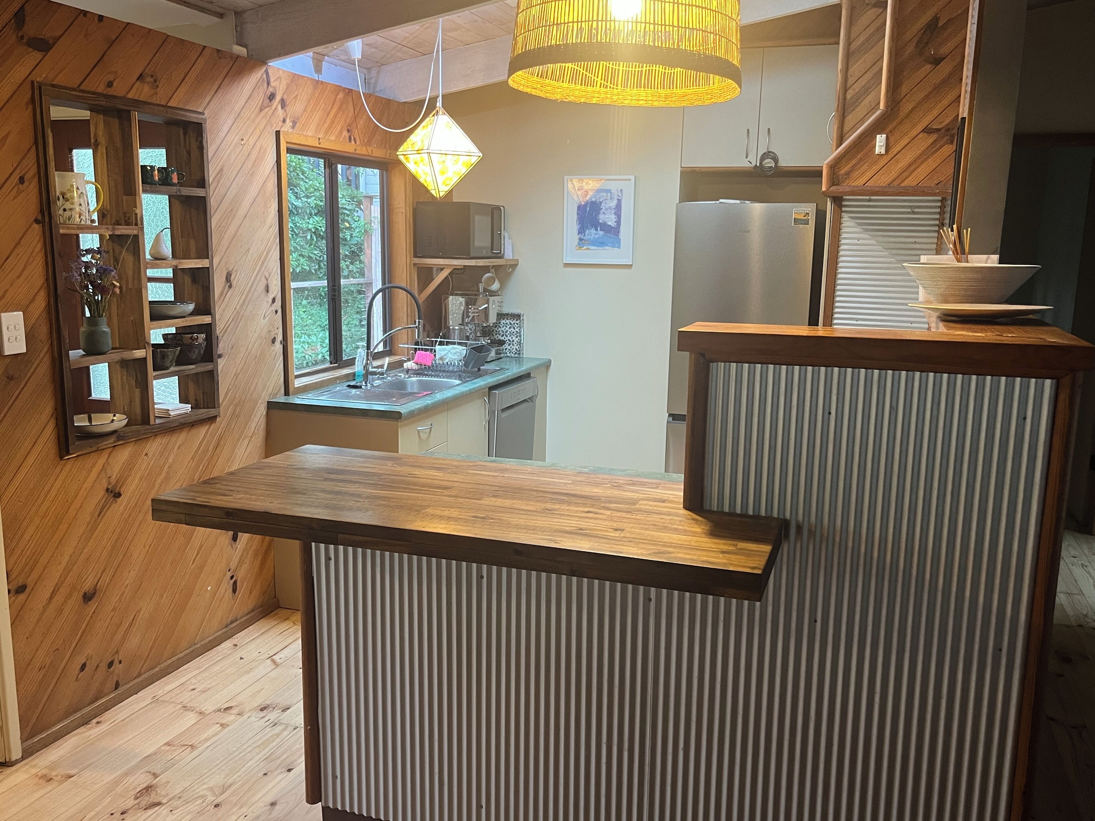 Eine moderne Küche mit Holzelementen, einer integrierten Spüle und einem Edelstahlkühlschrank.
