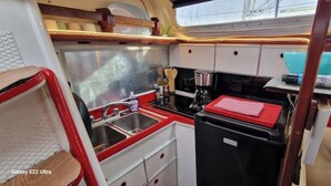 Een kleine keuken met een spoelbak, fornuis en opbergkasten.