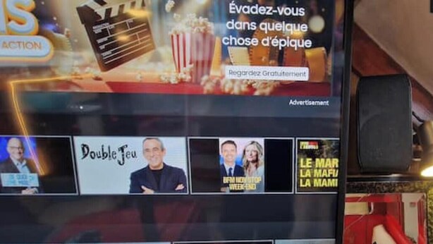 Een televisiescherm toont een filmreclame, met een emmer popcorn en een filmspoel. Onder het scherm staan drie kleinere afbeeldingen met tekst, vermoedelijk uit een nieuwsoverzicht of entertainmentprogramma.