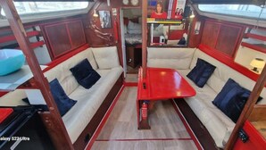 Bootinterieur met twee witte, beklede zithoeken, een centrale tafel en een blauwe schaal aan de linkerkant.