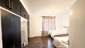 A bedroom with a wooden floor, a bed, a wardrobe, and a window with curtains. - Alat Residence (Kettering)