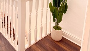 A staircase with white balusters, a potted plant with green leaves, and a wall-mounted mirror. - Alat Residence (Kettering)