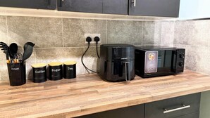 A kitchen with a coffee maker, a microwave, and three containers labeled coffee, sugar, and tea. - Alat Residence (Kettering)