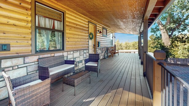 A wooden cabin with a porch, stone wall, wicker furniture, and a view of the outdoors. - Strawberry Cabin w/ Hot Tub Near Gila Nat'l Forest (Strawberry)