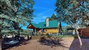 A rustic log cabin with a green roof, surrounded by trees and a gravel driveway. - Strawberry Cabin w/ Hot Tub Near Gila Nat'l Forest (Strawberry)