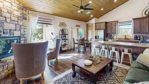 A spacious living area with a wooden ceiling, a fireplace, a dining area, and a kitchen with bar stools. - Strawberry Cabin w/ Hot Tub Near Gila Nat'l Forest (Strawberry)