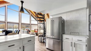 Una cocina moderna con una isla grande, electrodomésticos de acero inoxidable y vistas al exterior.