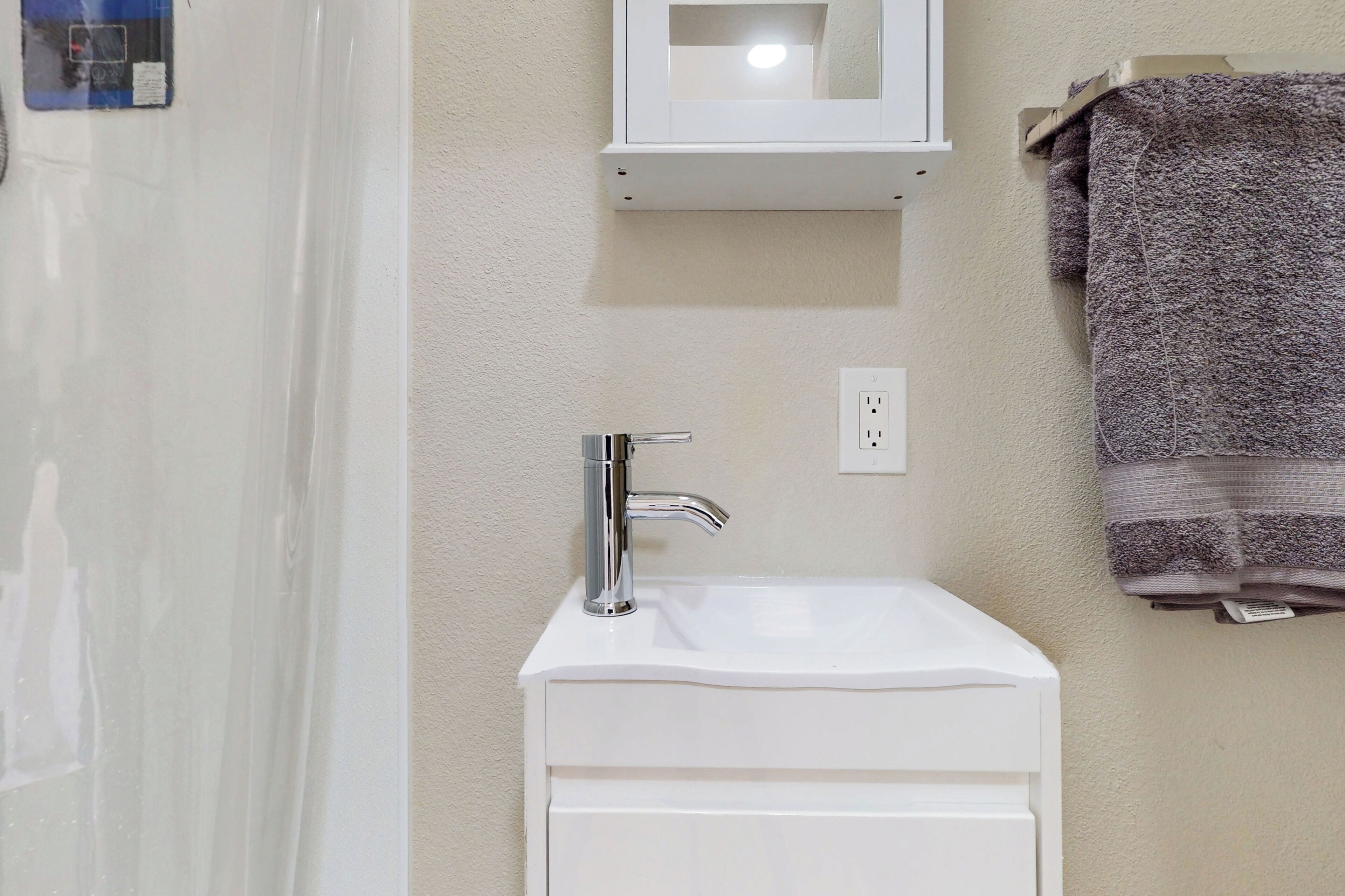 Un baño con un lavabo blanco, un espejo y una toalla colgada en la pared.