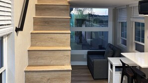 Une cuisine moderne avec un escalier en bois, un coin repas et une vue sur l’extérieur.