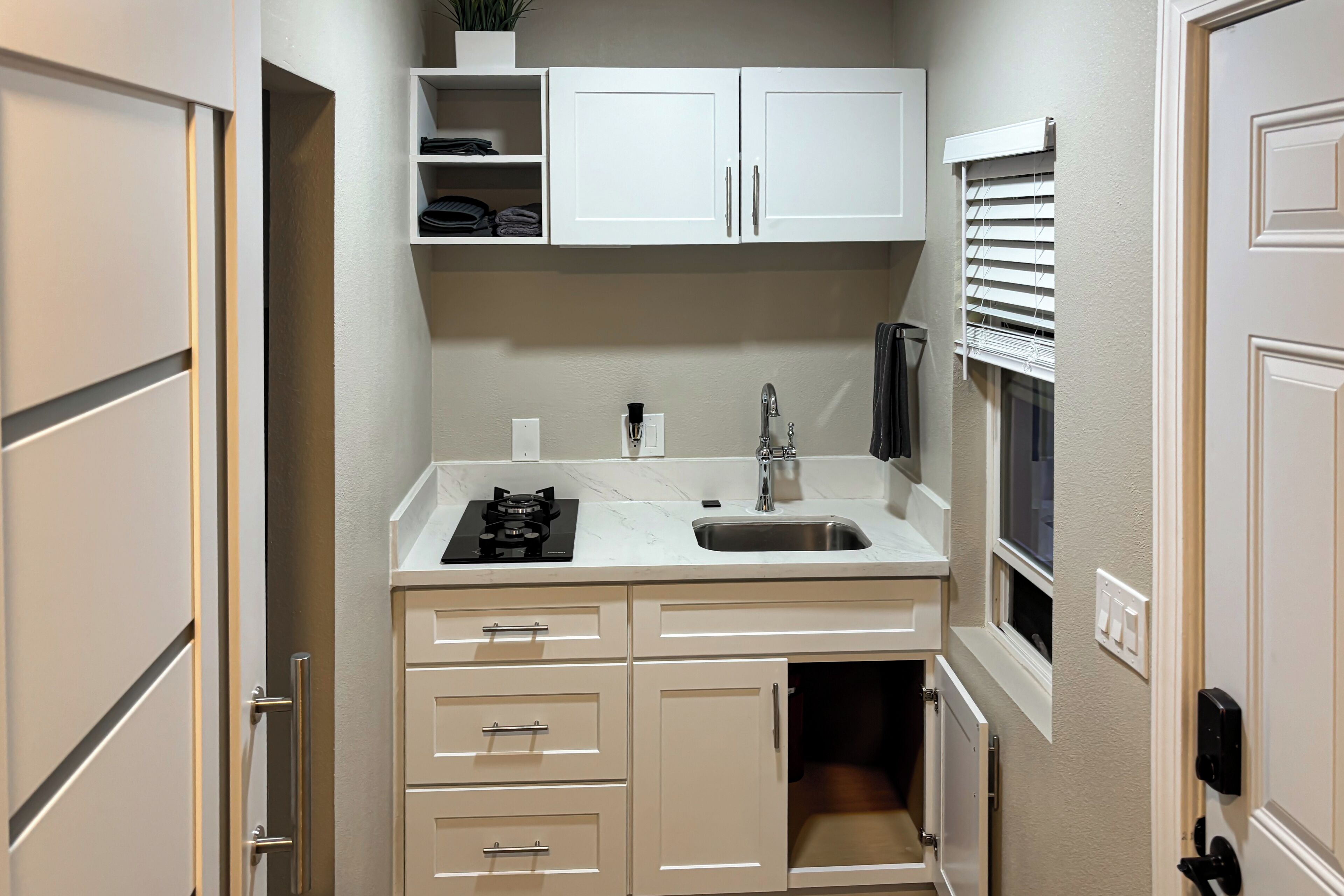 A compact kitchenette with a sink, stove, and storage cabinets.