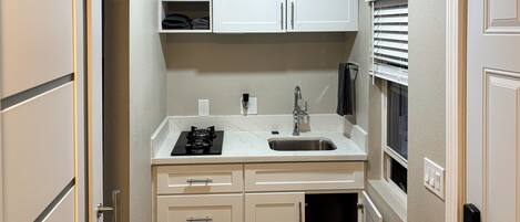A compact kitchenette with a sink, stove, and storage cabinets.