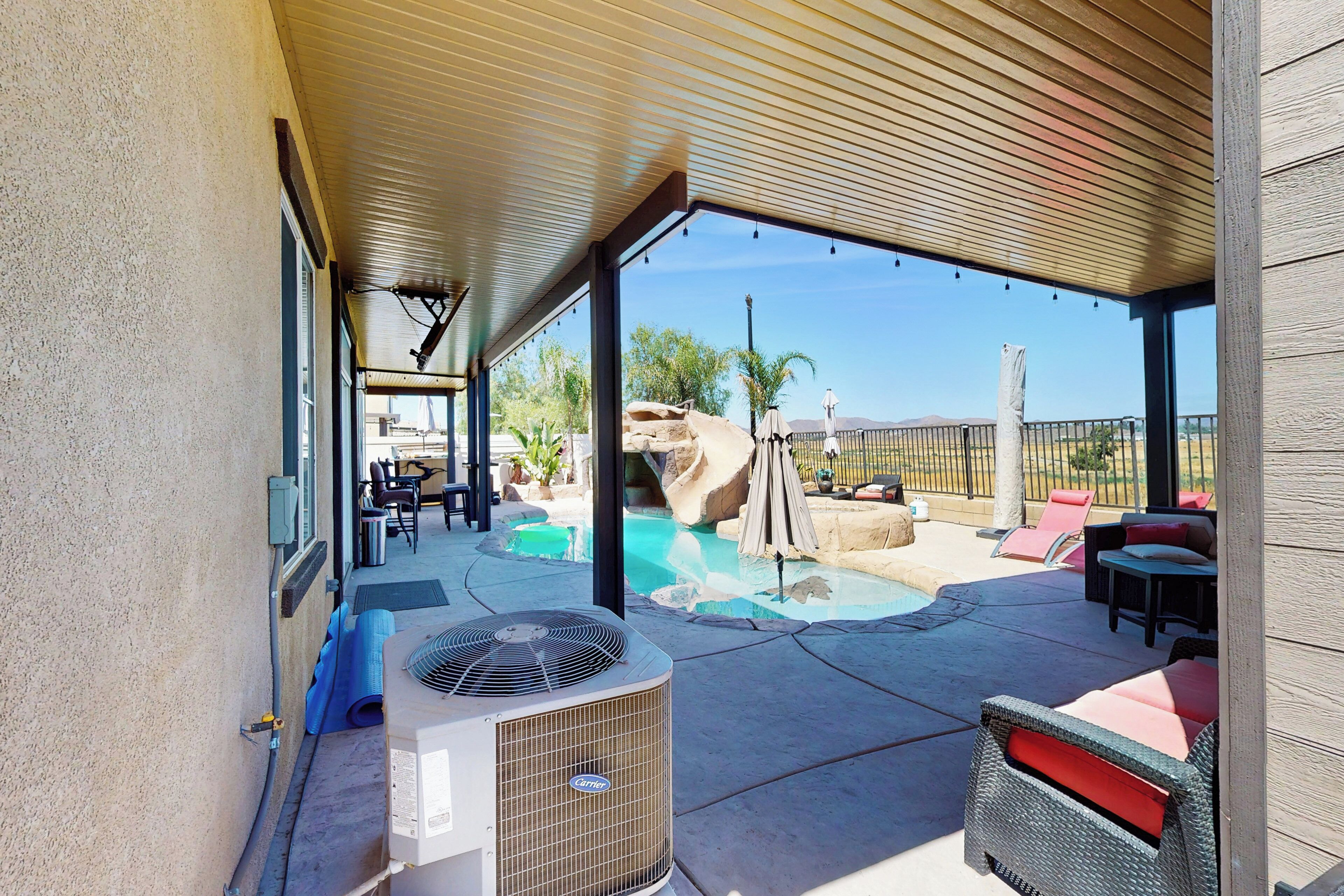 Un área de patio al aire libre con piscina, asientos y un equipo de aire acondicionado.