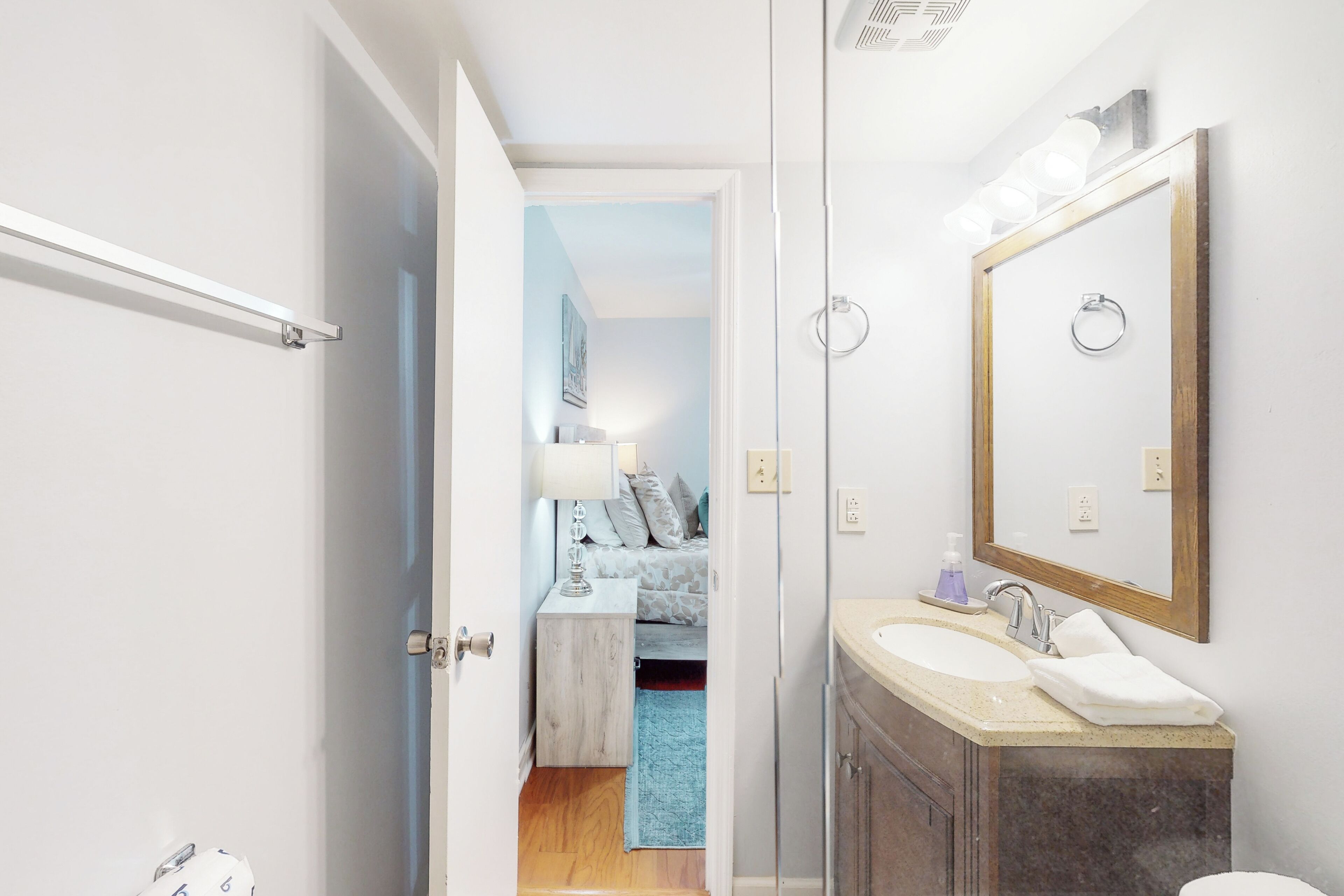 A bathroom with a sink, mirror, and towel rack.