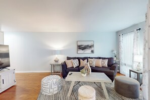 A living room with a dark-colored sofa, a coffee table, and a television. - Myrtle Beach Getaway w/ Outdoor Pool, Near Outlets (North Myrtle Beach)