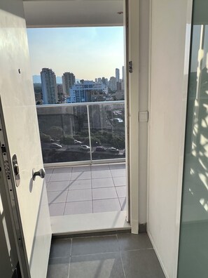 A balcony with a city view, a sliding door, and tiled flooring.