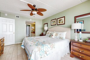 Ein Schlafzimmer mit Bett, Kommode, Deckenventilator und Spiegel.