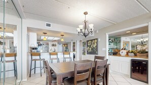 Ein geräumiger Essbereich mit Holztisch und -stühlen, einer Chandelierleuchtre und einer Küche im Hintergrund.