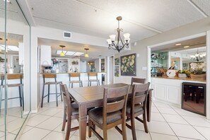 Ein geräumiger Essbereich mit Holztisch und -stühlen, einer Chandelierleuchtre und einer Küche im Hintergrund.