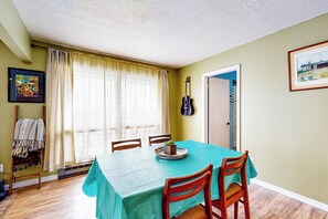 A dining area with a table set for four, a guitar on the wall, and a window with curtains. - Chautauqua Lake Views! Bemus Point Getaway (Bemus Point)