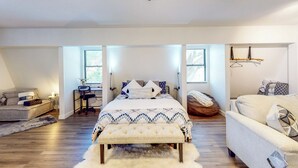 A spacious bedroom with a large bed, a desk, and a sofa.