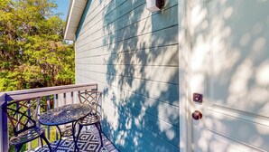 A house with a blue exterior, a white door, and a small porch with two chairs and a table.