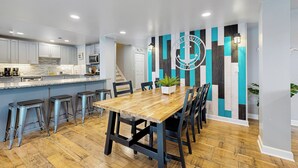 Een moderne keuken met een houten eettafel, barstoelen en een gestreept behang.