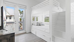 Quarto com cama embutida, uma pequena escrivaninha e janela com vista para um deck.