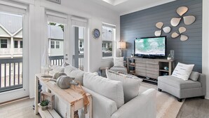 Uma sala de estar com sofá, televisão e um letreiro que diz "Beach House".