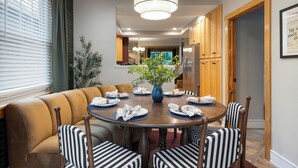 A dining area with a round table, striped chairs, and a vase of flowers. -  The Gopher House - Gym, Sauna, Game Room, Fire Pit (Minneapolis)