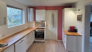 Eine kleine Küche mit Holzausziehtisch, Edelstahlgeräten und einem Fenster für natürliches Licht.