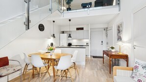 A modern apartment with a dining area, kitchen, and a staircase leading to a balcony.