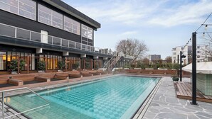A modern building with a swimming pool, outdoor seating, and a staircase leading to the upper levels.