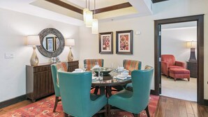 Un coin repas avec des chaises de couleur turquoise, une table en bois et un miroir décoratif.