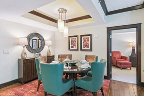 Un coin repas avec des chaises de couleur turquoise, une table en bois et un miroir décoratif.