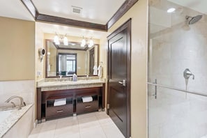 Une salle de bain avec un meuble-lavabo double, un grand miroir, une cabine de douche et une porte.